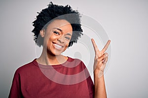 Young beautiful African American afro woman with curly hair wearing casual t-shirt standing smiling with happy face winking at the