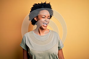 Young beautiful African American afro woman with curly hair wearing casual t-shirt winking looking at the camera with sexy