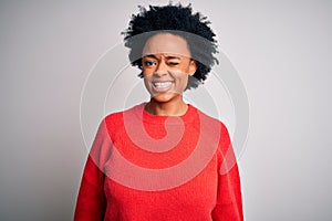 Young beautiful African American afro woman with curly hair wearing red casual sweater winking looking at the camera with sexy