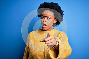 Young beautiful African American afro woman with curly hair wearing yellow casual sweater pointing displeased and frustrated to