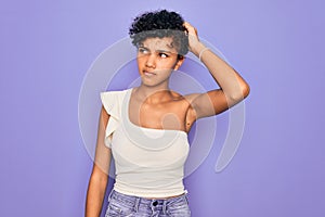 Young beautiful african american afro woman wearing casual t-shirt over purple background confuse and wondering about question