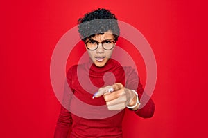 Young beautiful african american afro woman wearing turtleneck sweater and glasses pointing displeased and frustrated to the