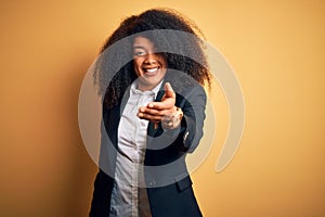 Young beautiful african american business woman with afro hair wearing elegant jacket smiling friendly offering handshake as