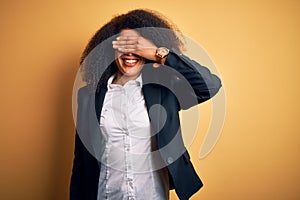 Young beautiful african american business woman with afro hair wearing elegant jacket smiling and laughing with hand on face