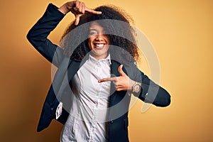 Young beautiful african american business woman with afro hair wearing elegant jacket smiling making frame with hands and fingers