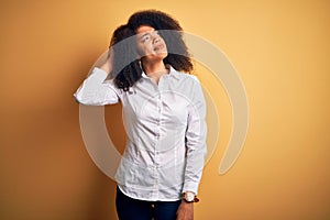 Young beautiful african american elegant woman with afro hair standing over yellow background confuse and wondering about question
