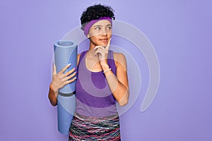 Young beautiful african american sporty woman wearing sportswear holding yoga mat serious face thinking about question, very