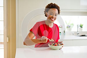 Young beautiful african american woman with afro hair eating healthy wholemeal cereals and berries as healthy breakfast