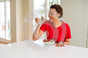 Young beautiful african american woman with afro hair eating healthy wholemeal cereals and berries as healthy breakfast