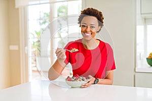 Young beautiful african american woman with afro hair eating healthy wholemeal cereals and berries as healthy breakfast