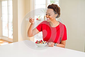 Young beautiful african american woman with afro hair eating healthy wholemeal cereals and berries as healthy breakfast