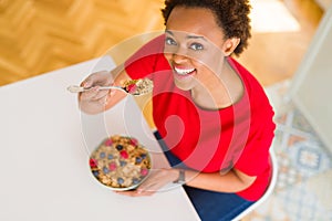 Young beautiful african american woman with afro hair eating healthy wholemeal cereals and berries as healthy breakfast