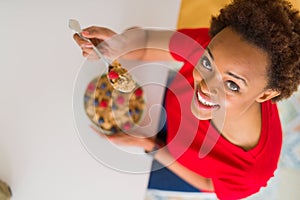 Young beautiful african american woman with afro hair eating healthy wholemeal cereals and berries as healthy breakfast