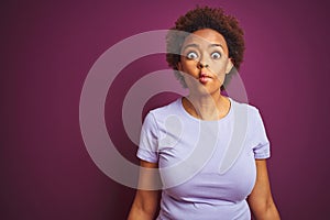 Young beautiful african american woman with afro hair over isolated purple background making fish face with lips, crazy and