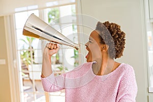 Young beautiful african american woman with afro hair screaming using megaphone