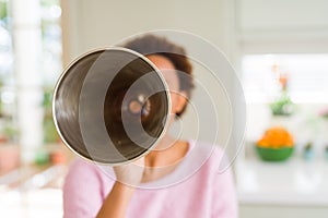 Young beautiful african american woman with afro hair screaming using megaphone