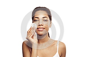 Young beautiful african american woman cleaning her face from makeup with white cotton pads on white background.