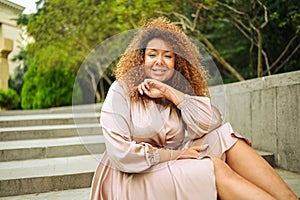 Young beautiful African American woman enjoys a walk in summer public green park. A happy woman plus size wearing silk