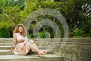 Young beautiful African American woman enjoys a walk in summer public green park. A happy woman plus size wearing silk