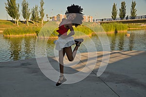 Young, beautiful African American woman jumping for joy happily outdoors on a sunny afternoon
