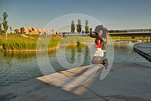 Young, beautiful African American woman jumping for joy happily outdoors on a sunny afternoon