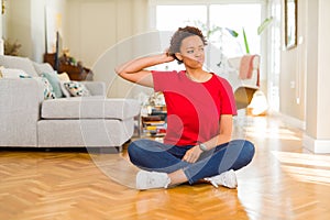 Young beautiful african american woman sitting on the floor at home confuse and wonder about question