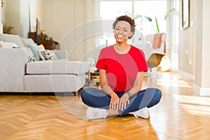 Young beautiful african american woman sitting on the floor at home with a happy and cool smile on face