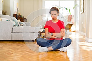 Young beautiful african american woman sitting on the floor at home skeptic and nervous, disapproving expression on face with