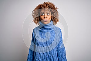 Young beautiful african american woman wearing turtleneck sweater over white background making fish face with lips, crazy and