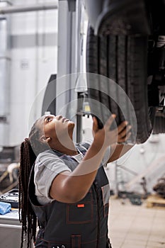 Young beautiful african mechanic woman adjusting the tire at repair garage