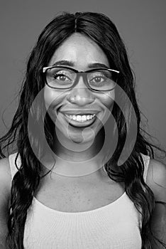 Young beautiful African woman wearing eyeglasses against gray background