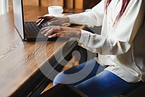 Young beautiful Afro-American businesswoman using laptop while working in cafe