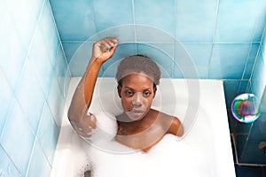 Young and beautiful Afro American woman takes a bubble bath in the bathtub. Beauty and hygiene concept