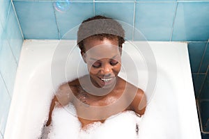 Young and beautiful Afro American woman takes a bubble bath in the bathtub. Beauty and hygiene concept