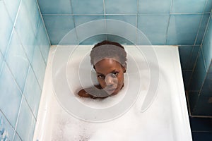 Young and beautiful Afro American woman takes a bubble bath in the bathtub. Beauty and hygiene concept