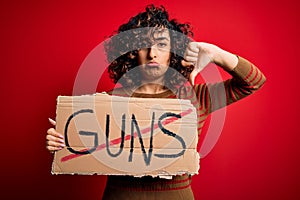 Young beautiful arab woman asking for peace holding banner with prohibited guns message with angry face, negative sign showing