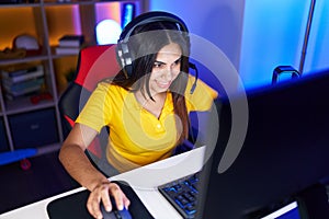 Young beautiful arab woman streamer playing video game using computer at gaming room