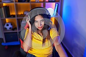 Young beautiful arab woman streamer smiling confident sitting on table at gaming room