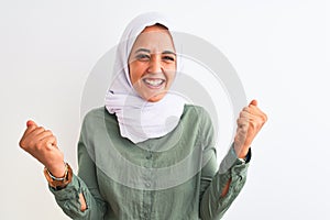 Young beautiful Arab woman wearing traditional Muslim hijab over isolated background celebrating surprised and amazed for success