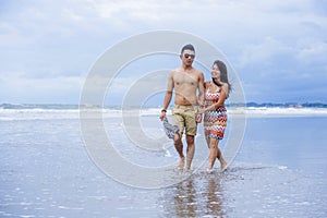 young beautiful Asian Chinese couple walking together on the beach happy in love enjoying holidays and relax smiling joyful in