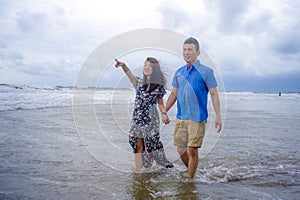 young beautiful Asian Chinese couple walking together on the beach happy in love enjoying holidays and relax smiling joyful in