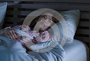 Young beautiful Asian Chinese girl lying on bed late night awake looking thoughtful suffering insomnia sleeping disorder feeling