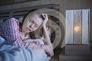 Young beautiful Asian Chinese girl lying on bed late night awake looking thoughtful suffering insomnia sleeping disorder feeling