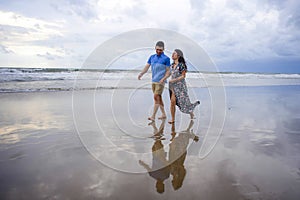 young beautiful and Asian Chinese romantic couple walking together holding hands on the beach happy in love enjoying holidays