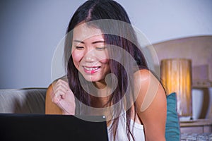 Young beautiful Asian Chinese student girl happy and relaxed at home couch using internet on laptop computer networking cheerful i