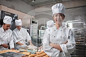 Young beautiful Asian female chef looks at camera, a cheerful smile in kitchen
