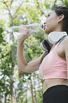 young beautiful asian fitness athlete woman drinking water after