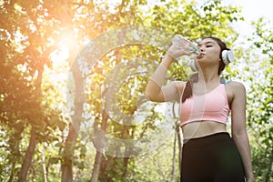 young beautiful asian fitness athlete woman drinking water after