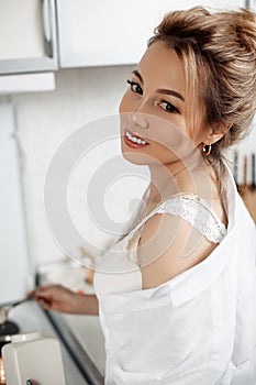 Young beautiful Asian girl in beige lace shorts,white shirt adds sugar to coffee. selective focus. small focus area