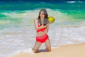 Young beautiful Asian girl in red cloth with coconut on the beach of a tropical island. Summer vacation concept.